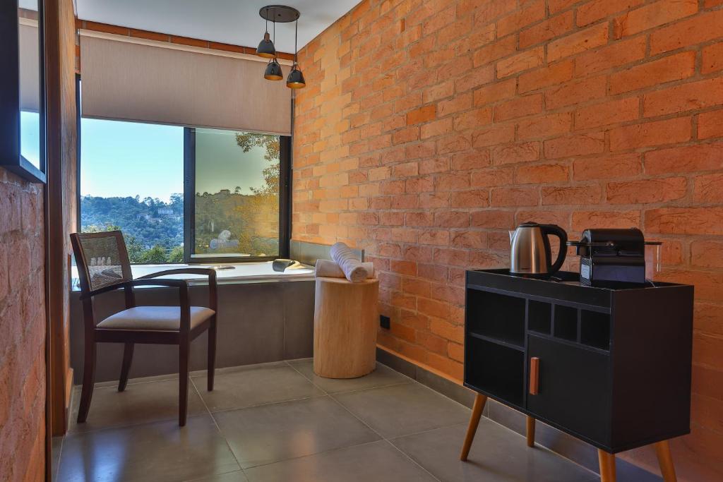 Área com banheira e janela ao lado, mesinha para cafeteira e chaleira.