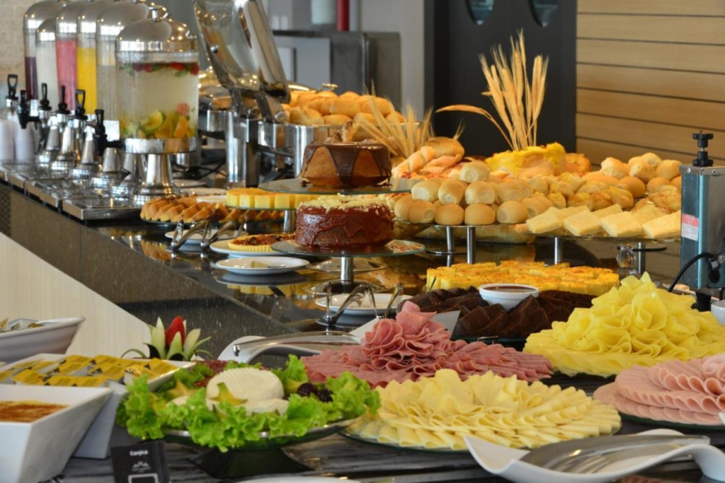 Buffet de café da manhã com pães, bolos, frios.