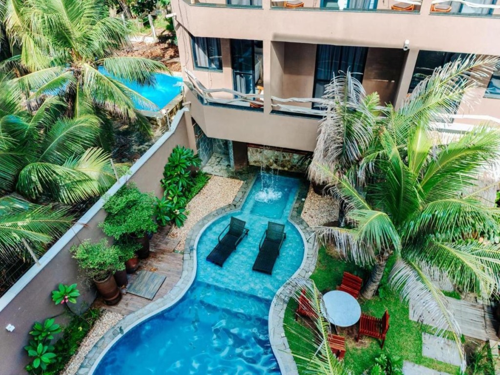 Vista aérea de piscina ao ar livre com jardim ao redor. Pousadas na praia do Futuro.