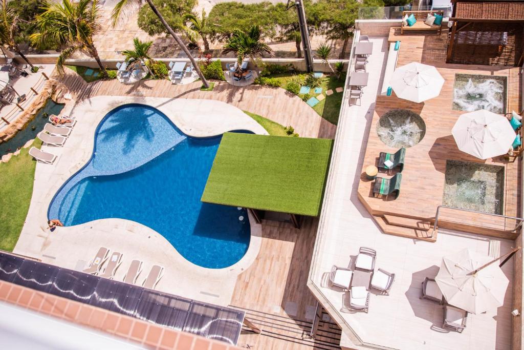 Ampla piscina ao ar livre, rodeada por palmeiras e três jacuzzis ao ar livre com sombreiros e espreguiçadeiras para relaxar. 