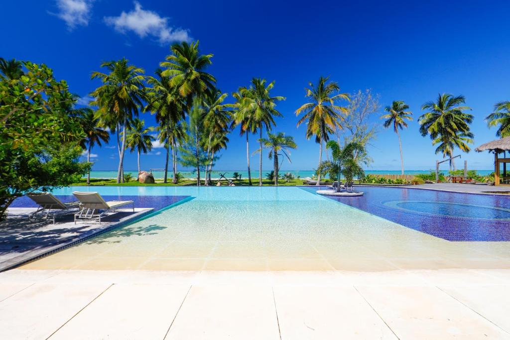 Espelho d'água e piscina ao ar livre, com coqueiros em pousadas para casal perto de Maceió.