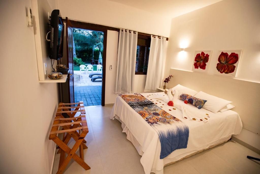 Cama extra grande em um quarto branco, com porta para a piscina. Nas pousadas para casal perto de Maceió.