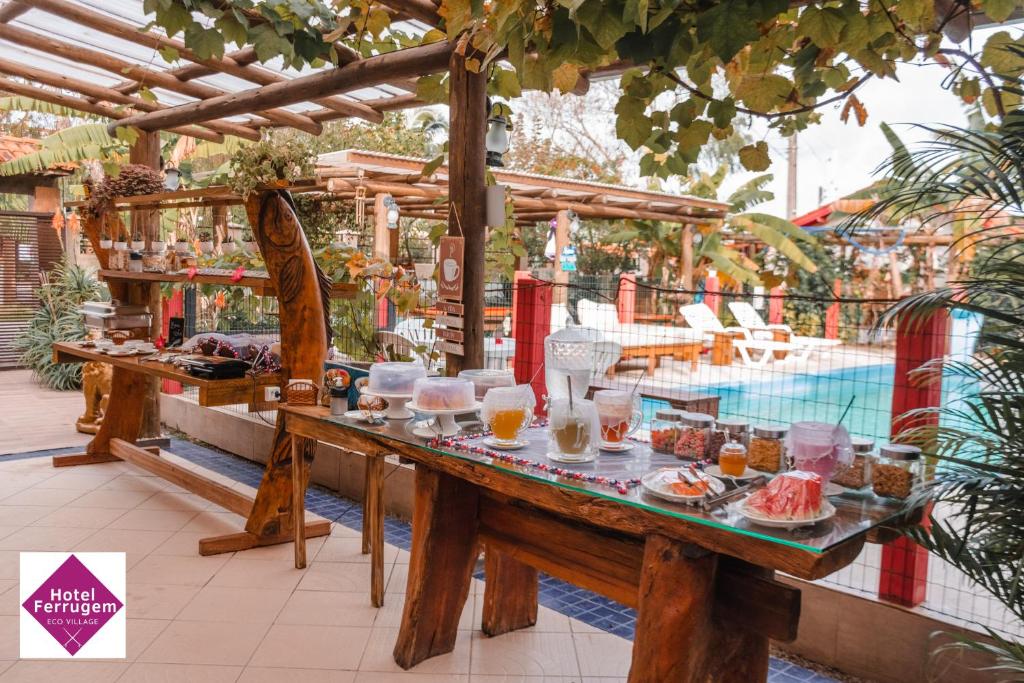 Mesa de café da manhã ao ar livre, com visual da piscina ao fundo.