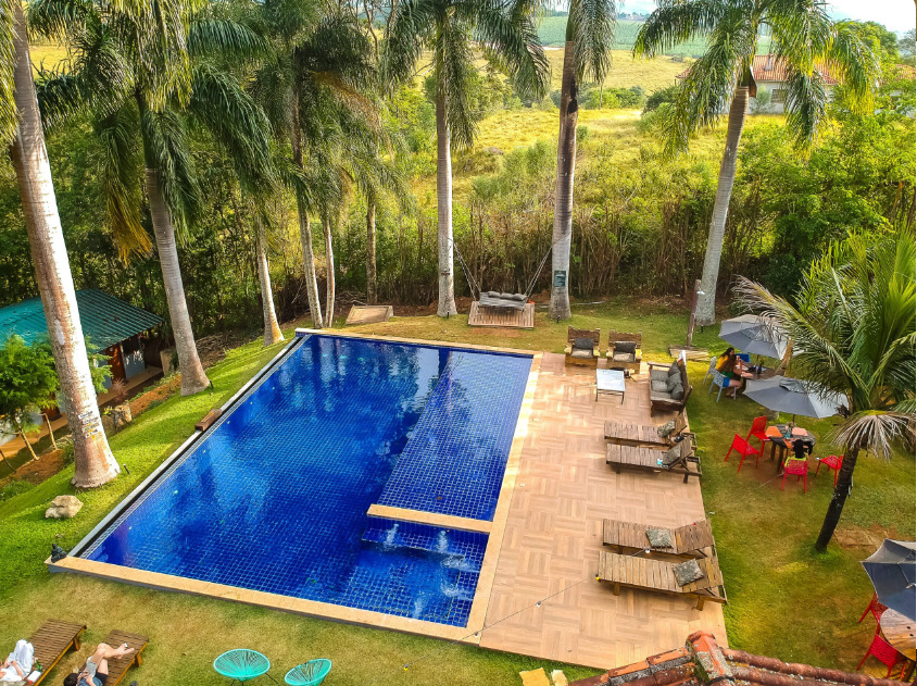 Vista aérea de piscina com borda infinita rodeada por palmeiras e com espreguiçadeiras.