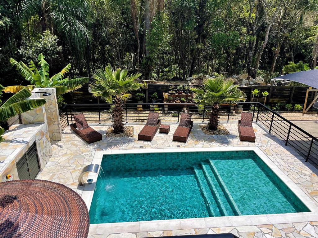 Piscina ao ar livre com espreguiçadeiras e algumas árvores em pousadas na Praia da Ferrugem.