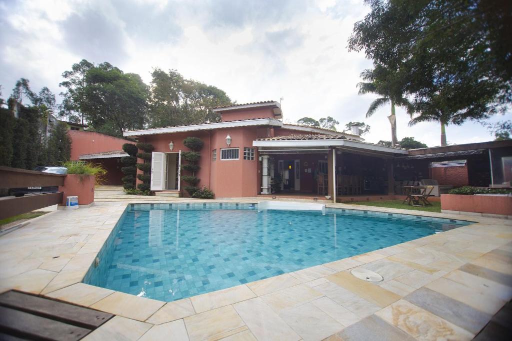 Piscina em área externa com casa ao fundo.