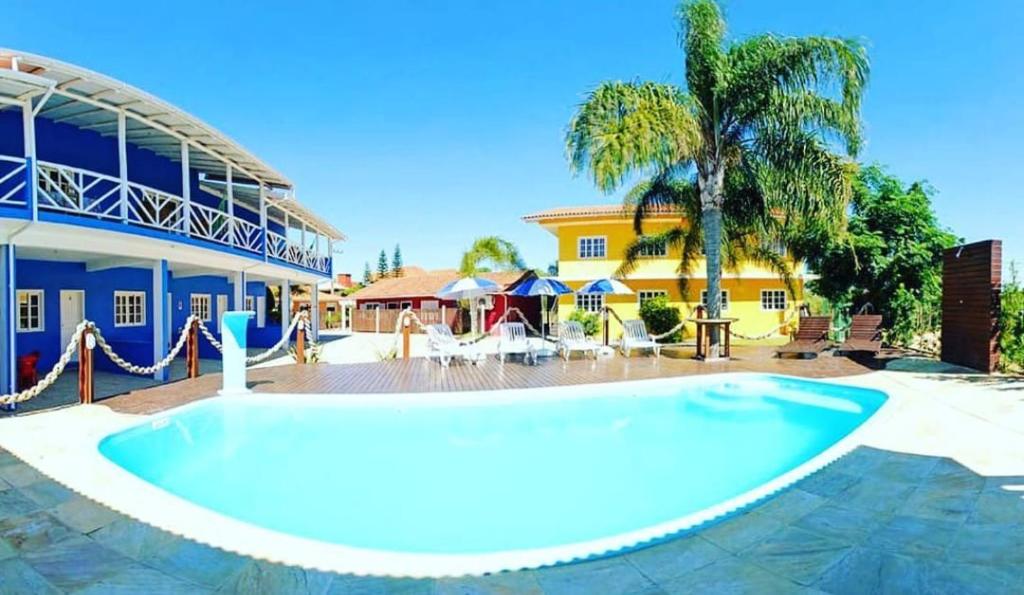 Panorama de uma piscina com os prédios de pousadas na praia da Ferrugem ao fundo.