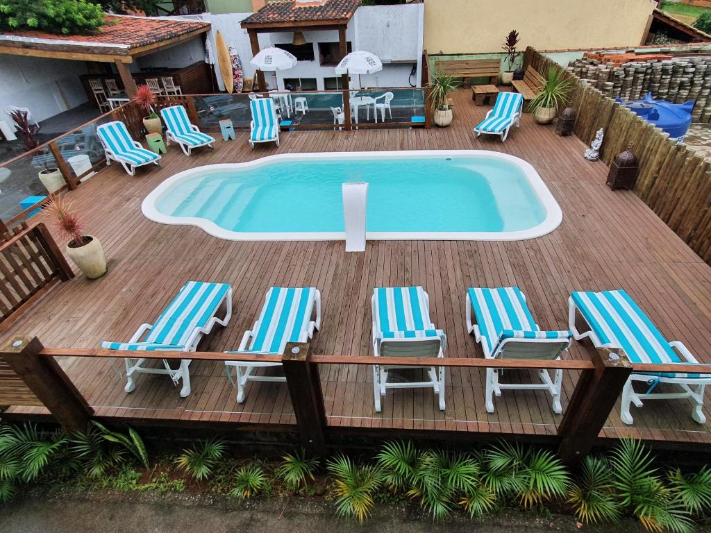 Área externa em deck de madeira com piscina e espreguiçadeiras.