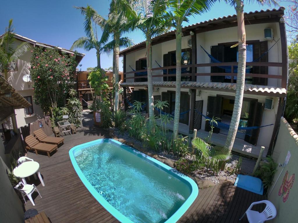 Piscina em deck de madeira com um pequeno jardim ao redor e espreguiçadeiras.