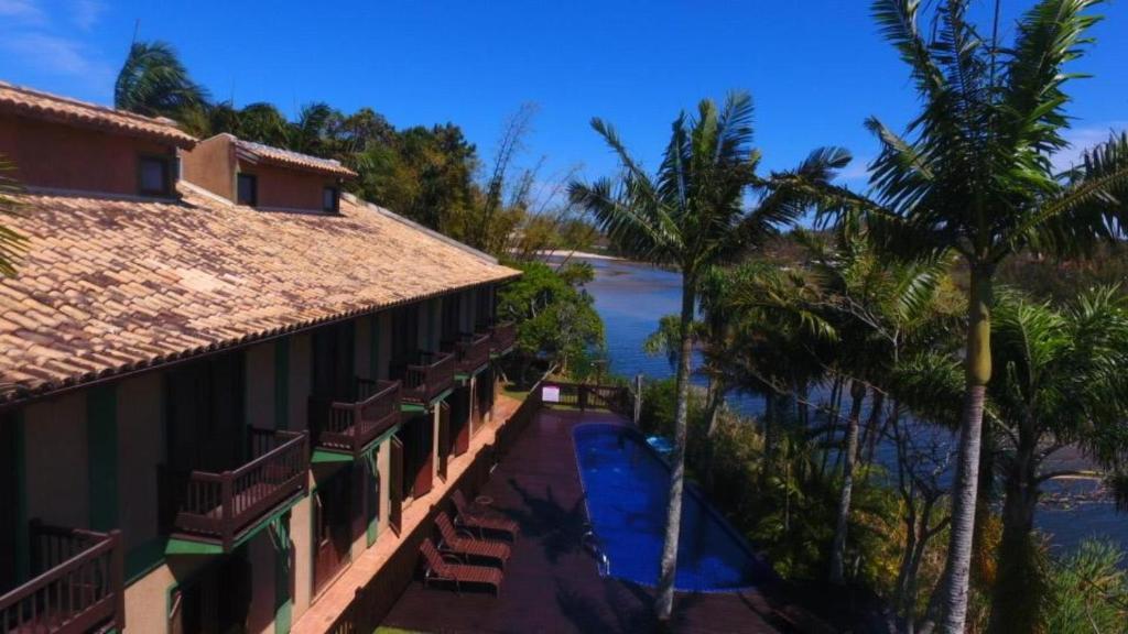 Prédio com varandas que dão para uma área com piscina e um lago. Em pousadas na praia da Ferrugem.