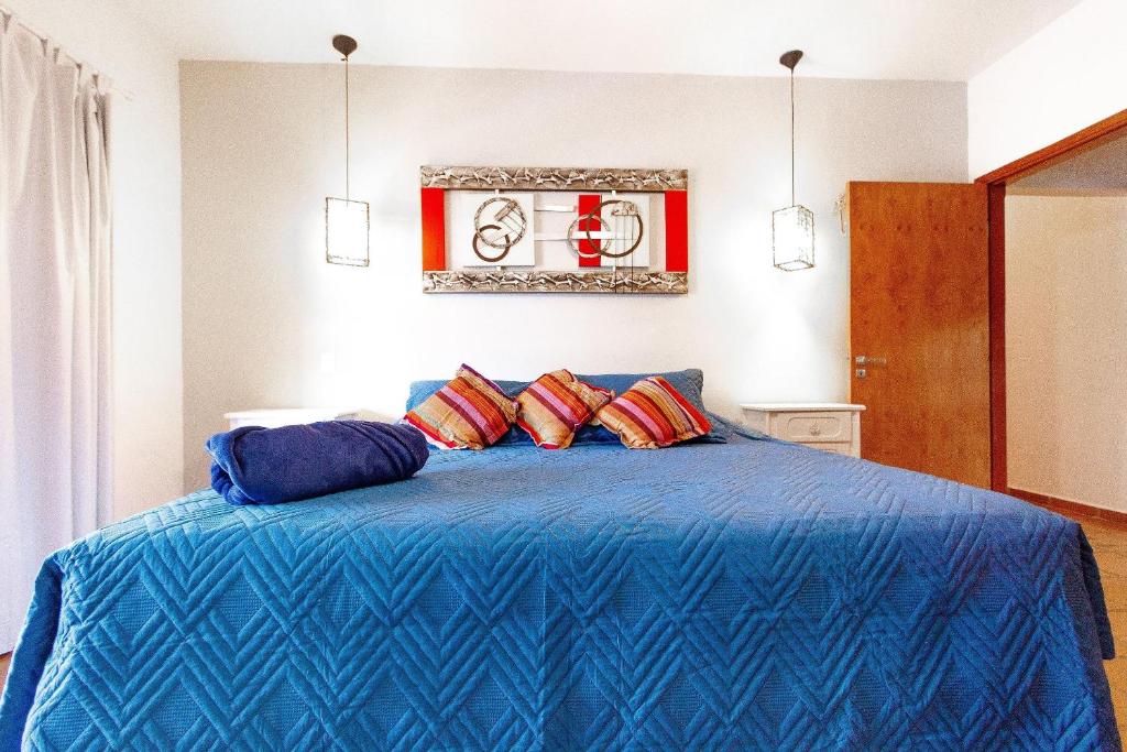 Cama extra-grande de casal com roupa de cama azul e decoração simples.