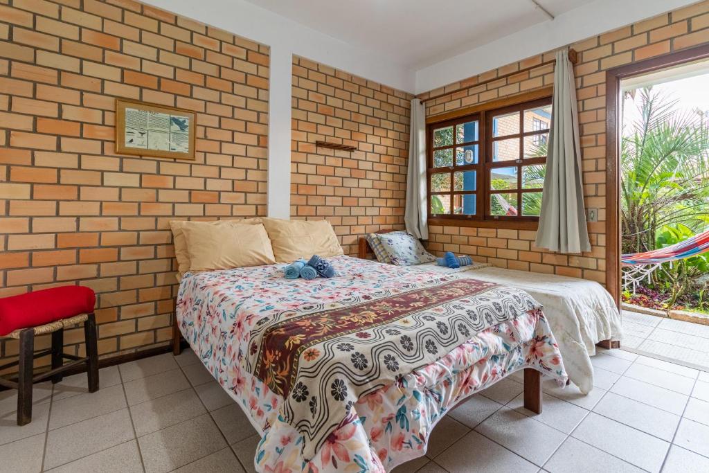 Quarto de tijolinhos aparente com cama de casal em pousadas na praia da Ferrugem.