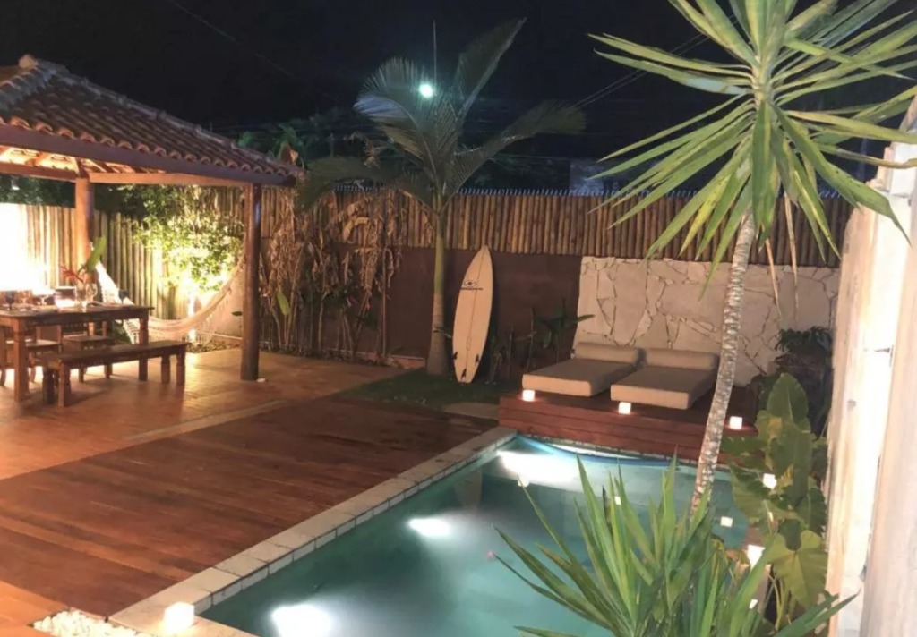 Piscina ao ar livre com deck de madeira próxima da varanda da casa.