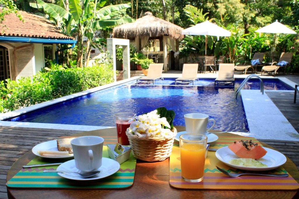 Piscina ao ar livre com espreguiçadeiras, guarda-sóis e uma mesa de café da manhã. Pousadas perto da praia da Baleia.