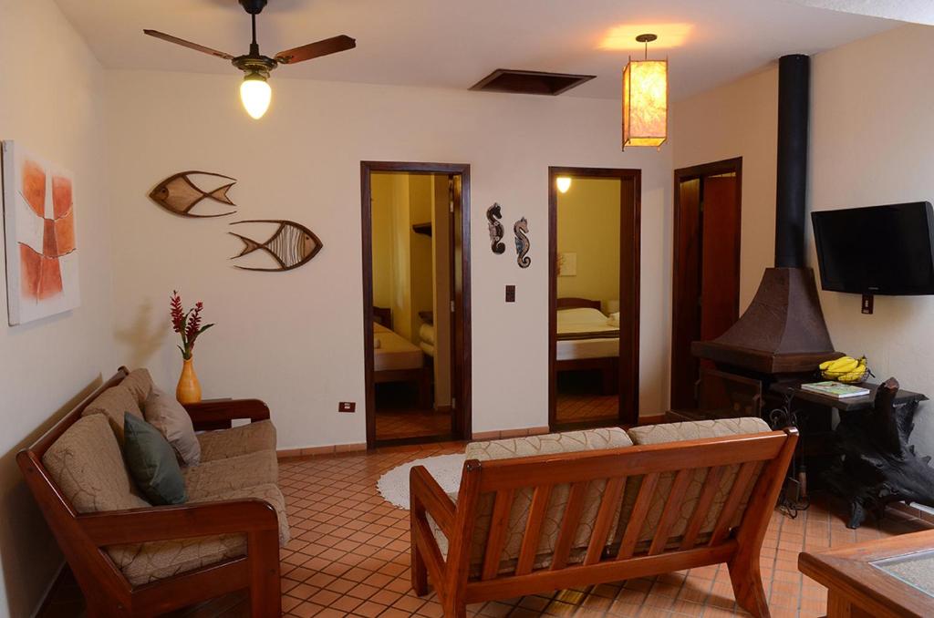 Sala de estar com sofás, lareira e porta para os dois quartos, em pousadas perto da praia da Baleia.