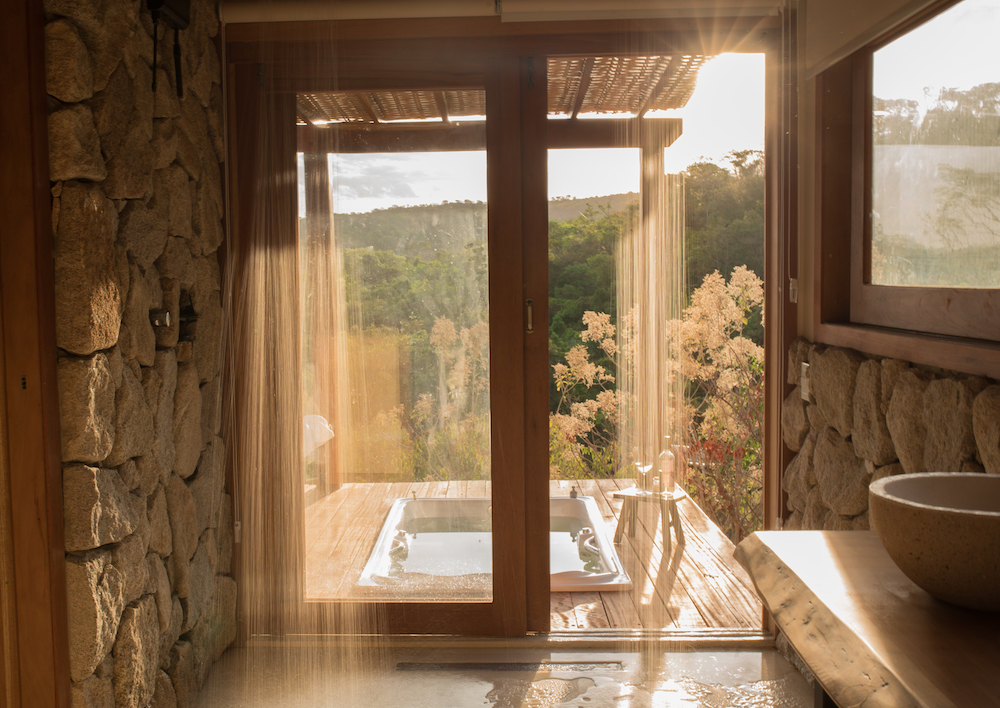 Suíte espaçosa com spa privativo em pousada romântica de Pirenópolis, com cores neutras, detalhes artesanais e clima de refúgio perfeito para viagens a dois