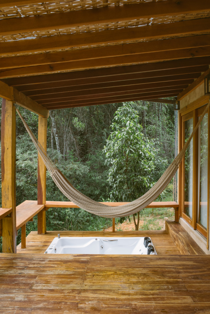 Suíte espaçosa com spa privativo em pousada romântica de Pirenópolis, com cores neutras, detalhes artesanais e clima de refúgio perfeito para viagens a dois